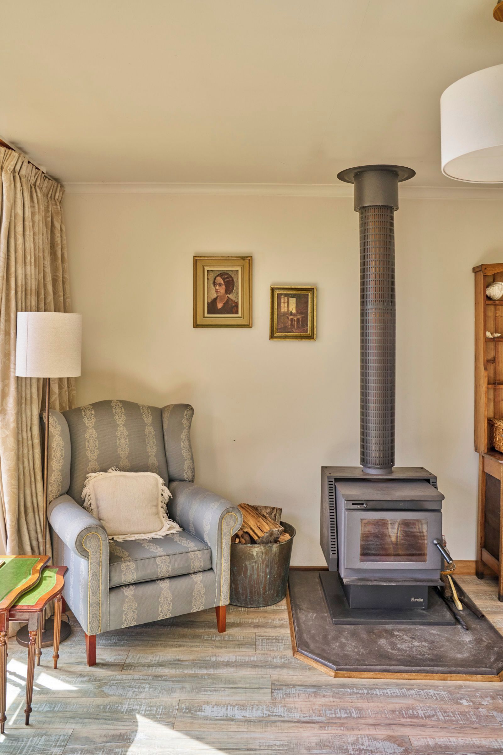 A cozy living room with a sofa, a fireplace, and two framed pictures on the wall.