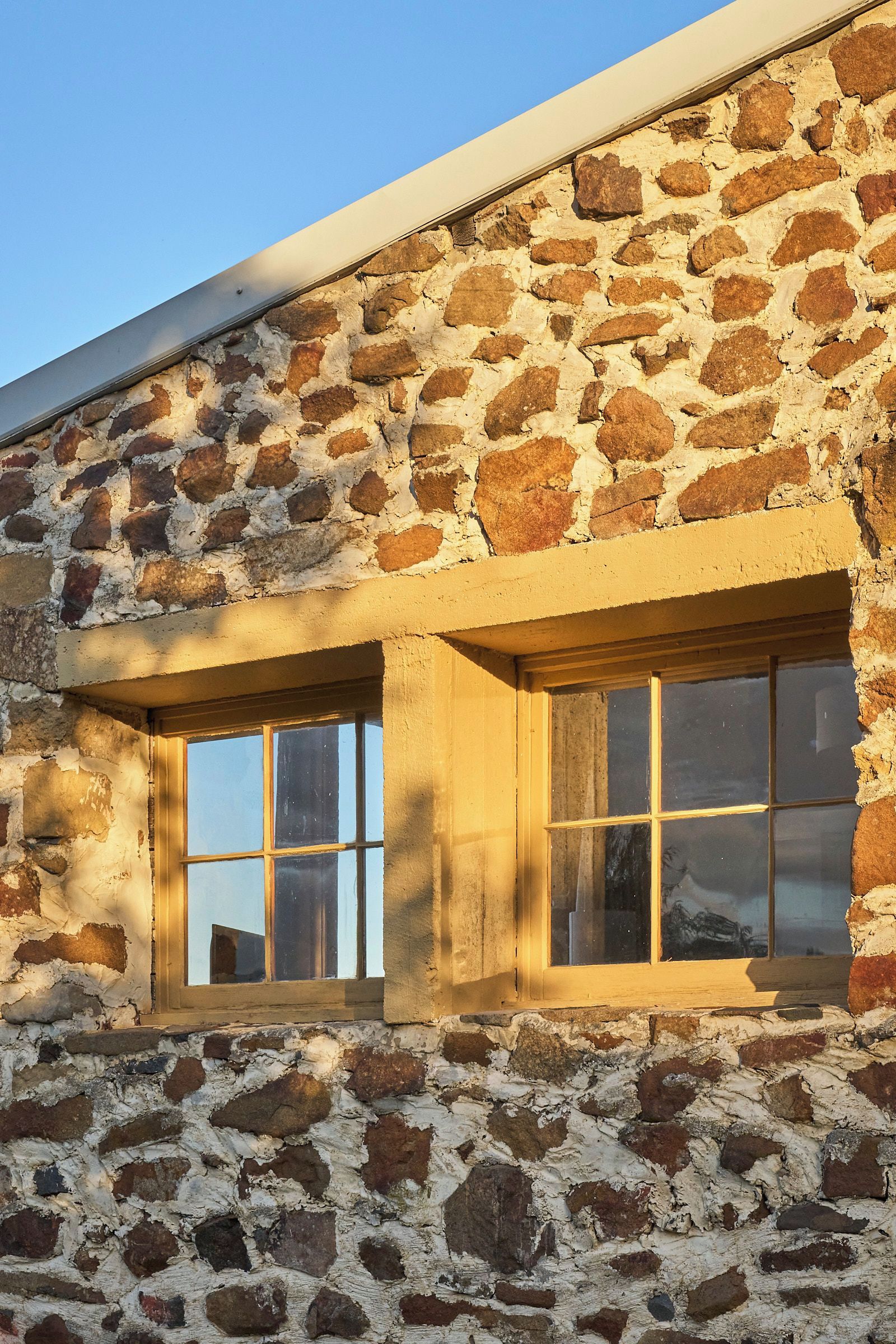 A stone building with two windows and a sloped roof.