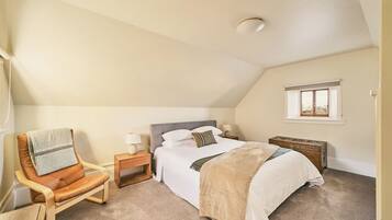 A bedroom with a single bed, a nightstand, a chair, a window, and a ceiling light.