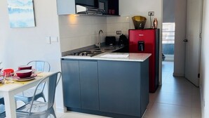 A modern kitchen with a central island, a dining area with a table and chairs, and a red refrigerator. - Apartamento 2 dormitorios, cerca de lo mas destacado de la ciudad y aeropuerto (Santiago)