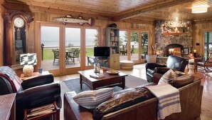 Un intérieur en bois avec une cheminée, un téléviseur et une vue sur l’extérieur.