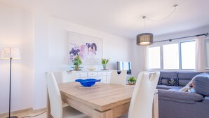 Un comedor moderno con una mesa de madera y sillas blancas, un tazón azul y una lámpara colgante.