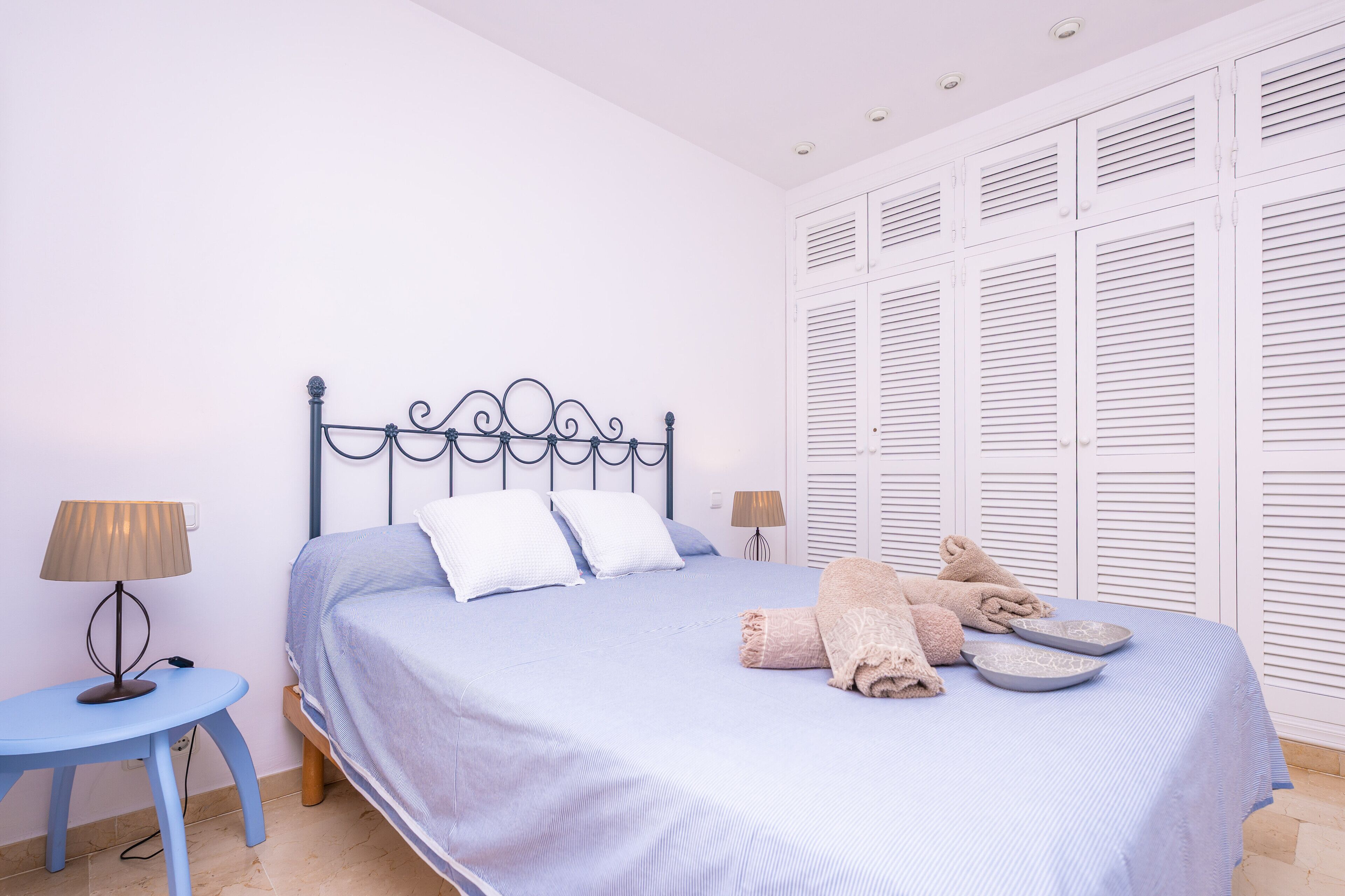 Een slaapkamer met een bed, twee nachtkastjes en een garderobe met verstelbare deuren.