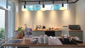 Un comptoir pour prendre le petit-déjeuner, avec du café et des toasts, une bouilloire, un four à micro-ondes et un distributeur d’eau.