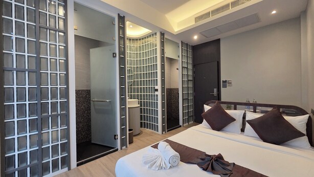 Une chambre d’hôtel avec un lit, une salle de bain avec douche et une paroi en verre.