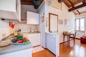 A modern kitchen with white cabinets, a sink, and a dining area with a table and chairs. - Le Fontane With View Lake (Gardone Riviera)