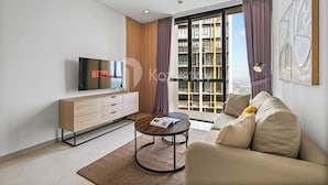 A modern living room with a sofa, coffee table, TV, and a large window with curtains. - Osvara by Kozystay - Cilandak (Jakarta)