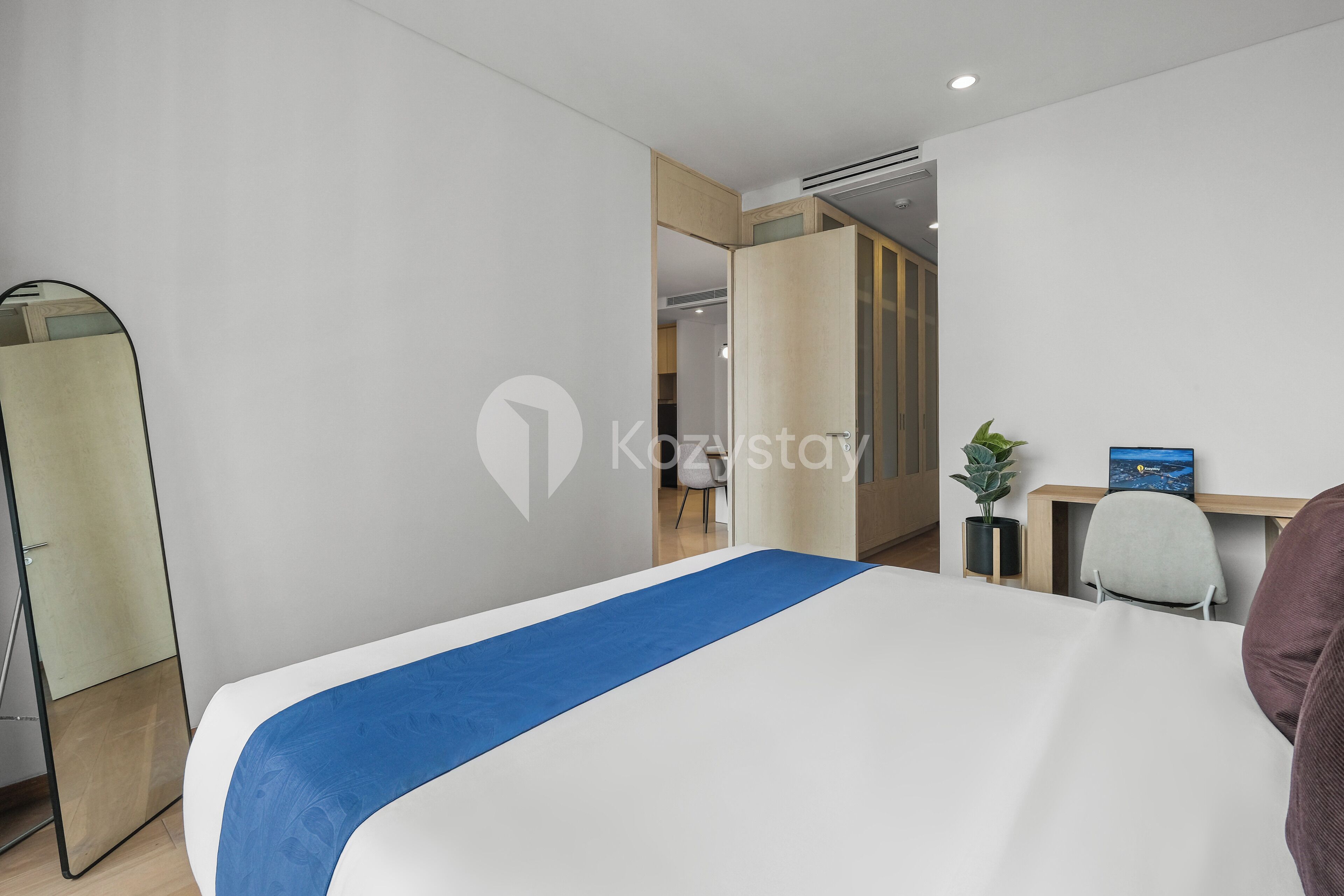 Een moderne hotelkamer met een bed, een bureau, een stoel en een garderobe.