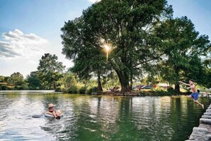A lake with a person in a boat and another person jumping into the water. - 5/2 (two kings), fireplace, hot tub, firepit (Blanco)