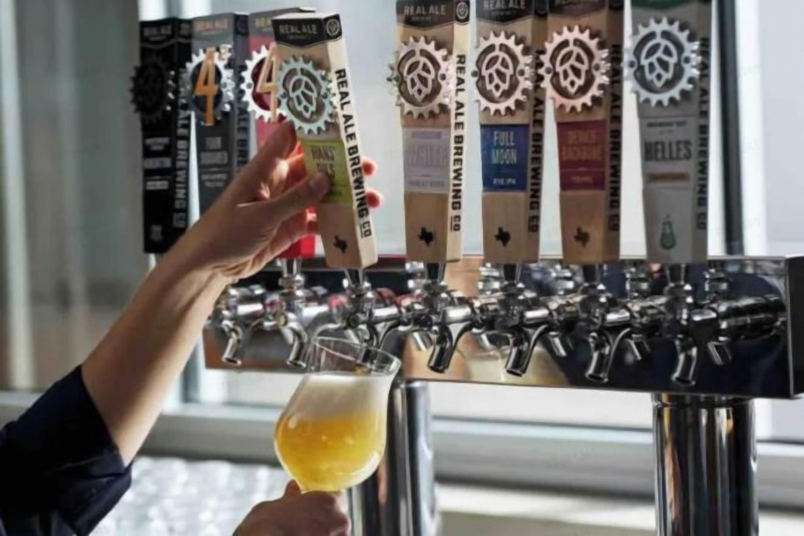 A hand selecting a beer from a tap labeled 'REAL ALE BREWING.'