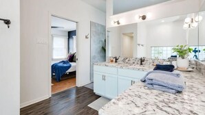 Een moderne badkamer met een marmeren aanrechtblad, een grote spiegel en een wastafel.