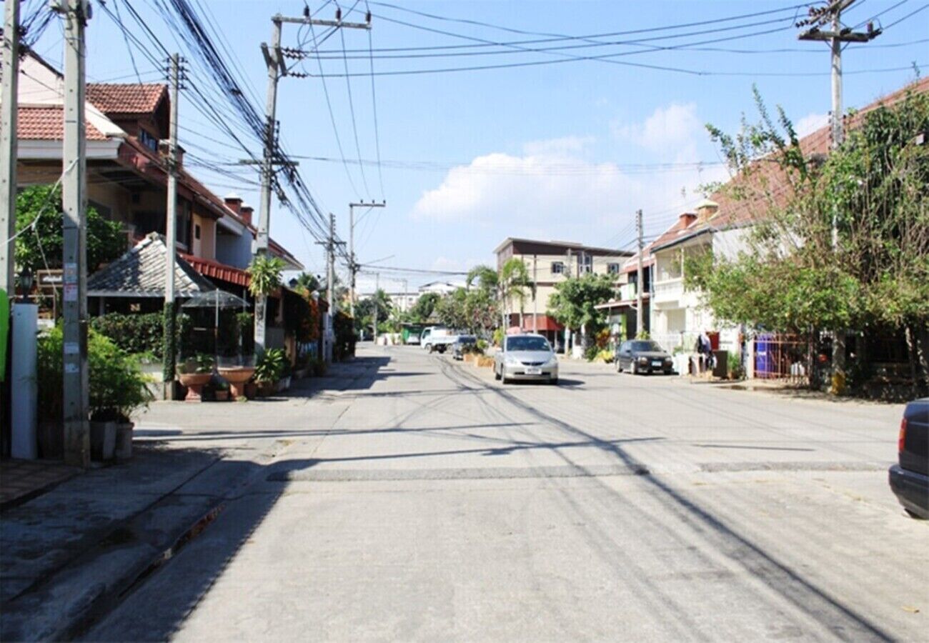 A street with residential buildings, power lines, and parked cars.
