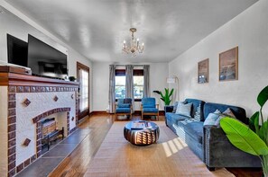 A living room with a fireplace, a sofa, two armchairs, a coffee table, and a television. - Charming Retreat Near Bricktown & Parks (Oklahoma City)