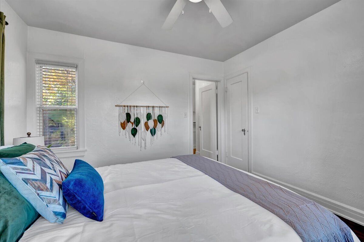 A bedroom with a bed, a wall hanging, and a door.