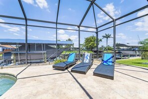A covered outdoor area with lounge chairs and a pool. - Reel Serenity (Cape Coral)