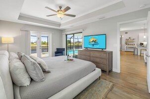 Un dormitorio con cama, televisión y vista a una piscina.