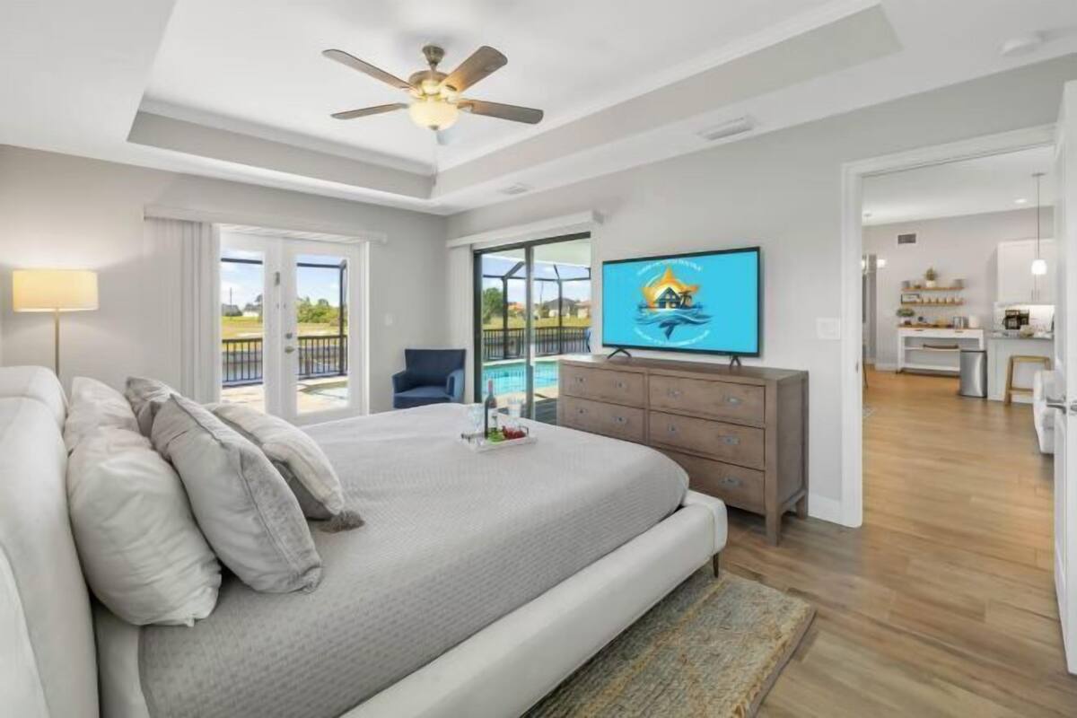 Camera da letto con un letto, una ventola a soffitto, una TV, una cassettiera e vista all'esterno.