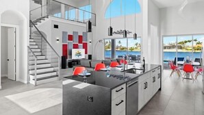 Una cucina moderna con isola centrale, una scala e vista sull'oceano.