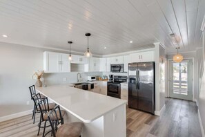 A modern kitchen with white cabinetry, stainless steel appliances, and a large island.