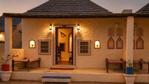 A traditional building with a thatched roof, a central doorway, and multiple small windows with decorative frames. - Hotel Ratan Mahal Palace (Ratangarh)