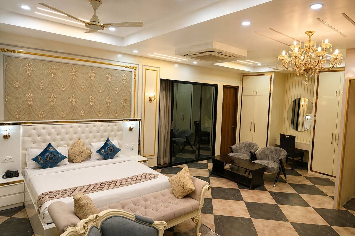 A bedroom with a bed, a sofa, a desk, and a chandelier.