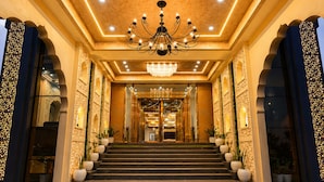 A grand hotel lobby with a chandelier, ornate walls, and a staircase leading to the entrance. - Hotel Ratan Mahal Palace (Ratangarh)