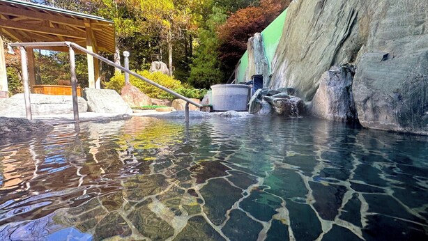 A clear pool with a wooden deck and a stone wall. - Livemax Resort HidaTakayama GaryunoSato (Takayama)
