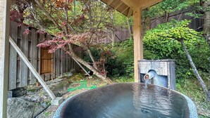 A traditional Japanese onsen with a wooden structure, a stone bath, and a wooden fence in the background. - Livemax Resort HidaTakayama GaryunoSato (Takayama)