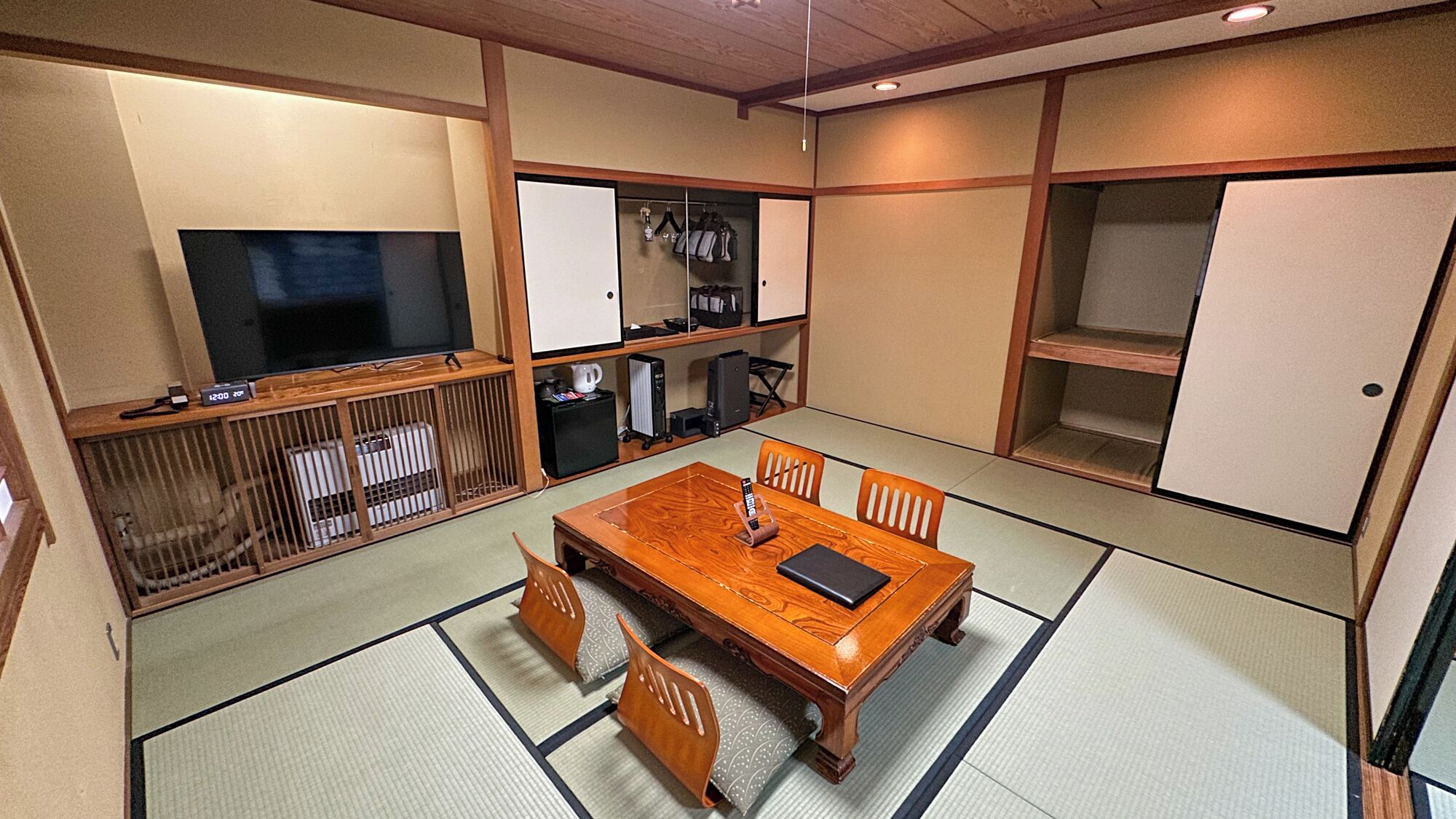 A traditional Japanese-style room with tatami flooring, a wooden dining table, and a television.