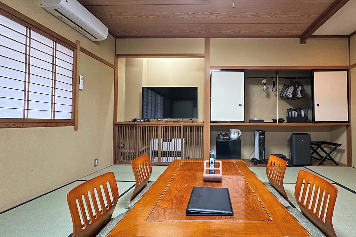 Una habitación tradicional japonesa con suelo de tatami, una mesa de madera y un televisor.