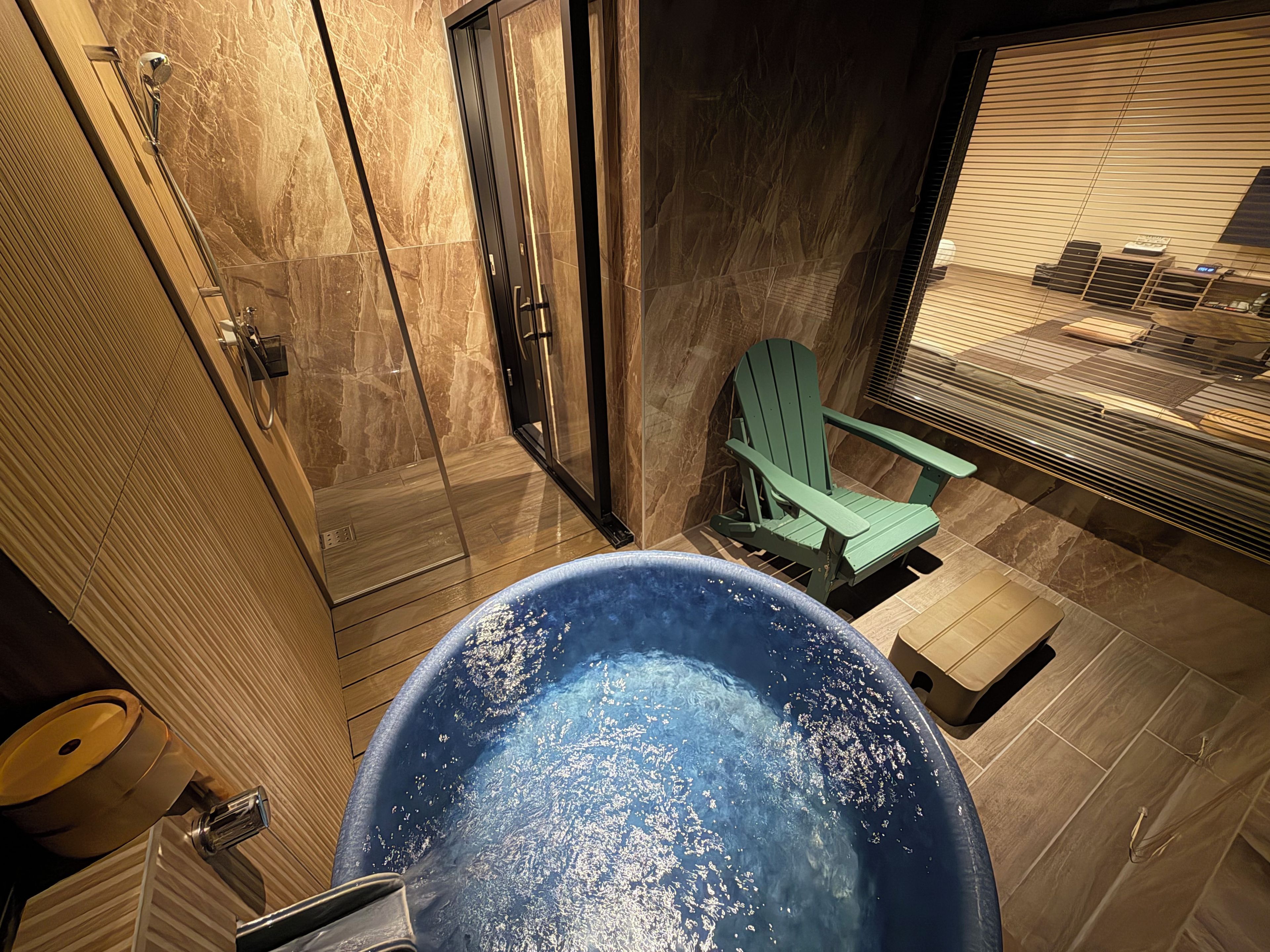 A bathroom with a bathtub, a shower, and a green chair.