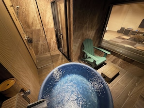 Une salle de bain avec une baignoire, une douche et un fauteuil vert.