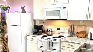 Una cocina moderna con gabinetes blancos, un lavaplatos de acero inoxidable, un microondas, una estufa y un refrigerador.