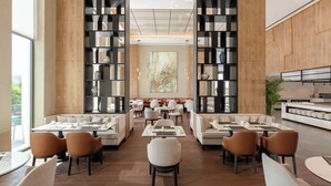 A modern dining area with high wooden walls, multiple seating options, and a large window providing natural light. - Aghdam City Hotel (Aghdam)