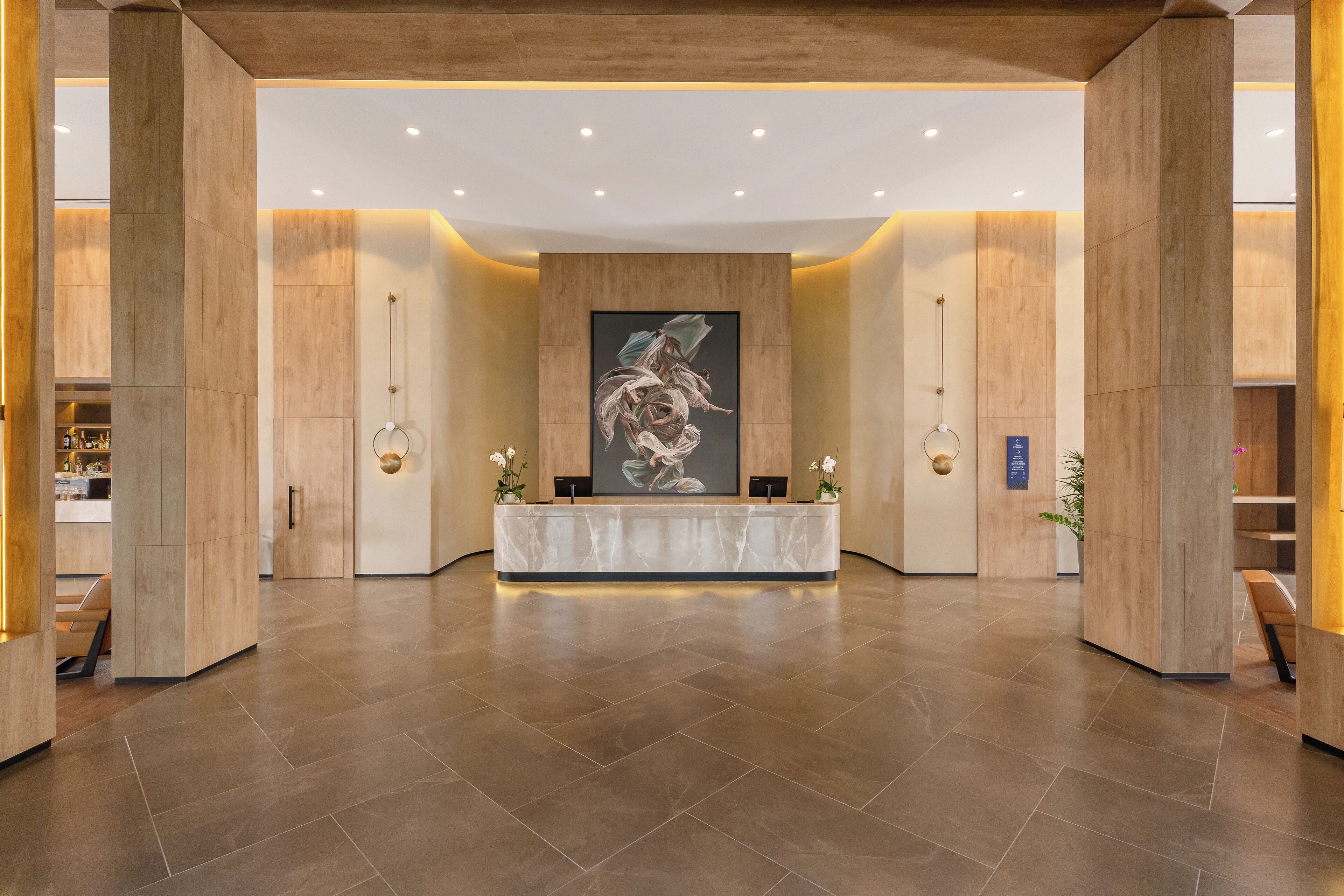 A reception area with a marble counter, wooden pillars, and a large abstract painting on the wall.