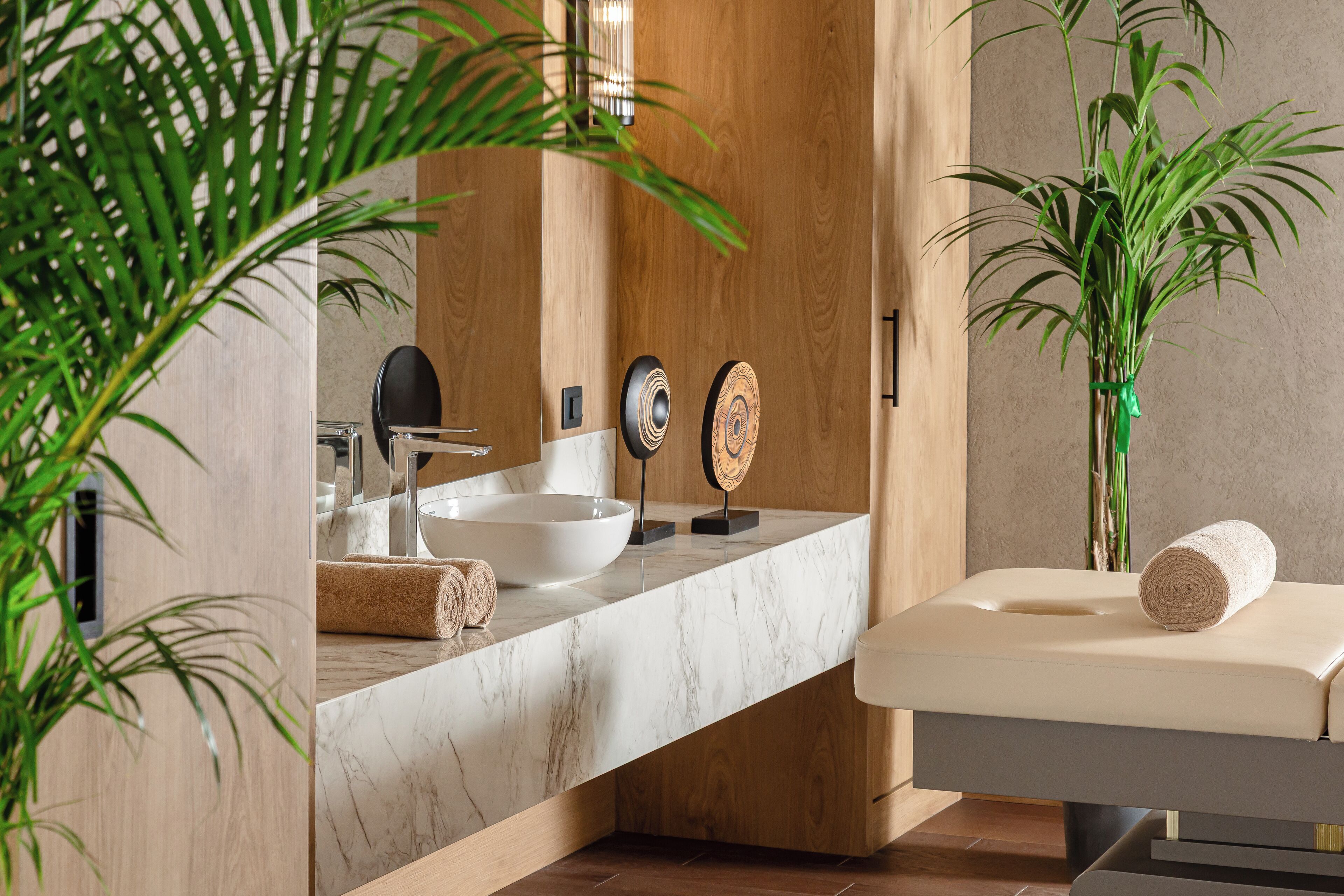 A modern bathroom with a marble countertop, a sink, a towel, and a massage table.