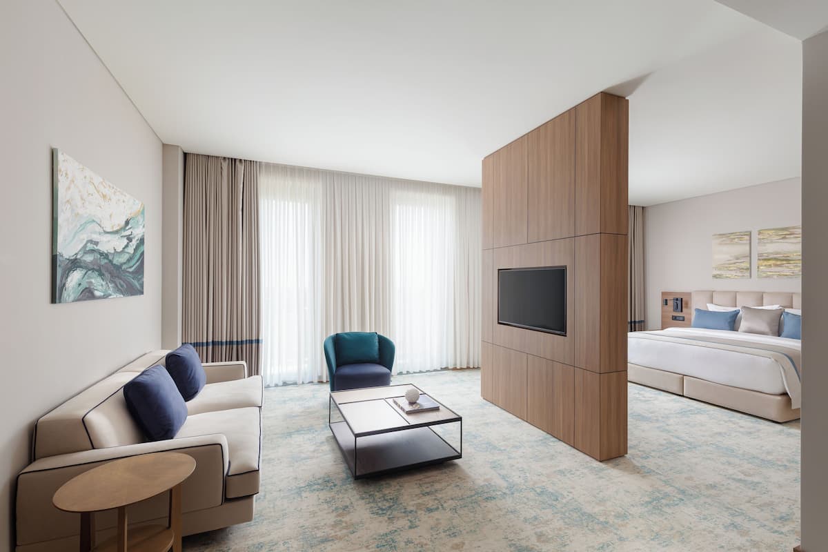 Une chambre d’hôtel moderne équipée d’un canapé, d’un fauteuil et d’une télévision.