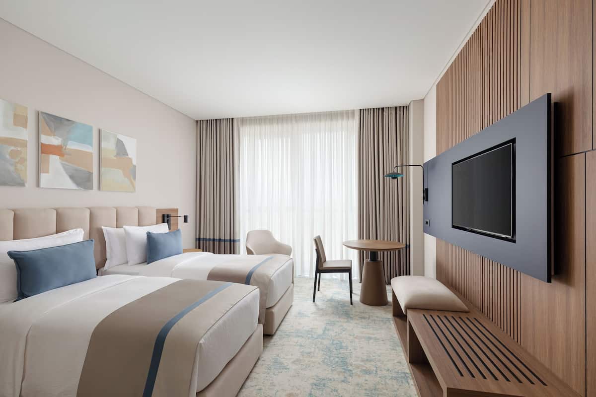 Une chambre d’hôtel avec deux lits, une télévision, une petite table et une chaise.