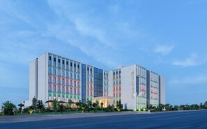 A modern hotel with a symmetrical facade, multiple floors, and a prominent entrance.