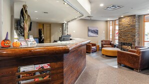 A reception area with a wooden reception desk, a stone accent wall, and leather seating. - Whistler Village Stroll Condo with AC and Free Parking (Whistler)
