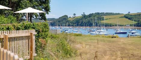 A marina with multiple boats docked, surrounded by greenery and hills.