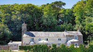 A stone house with a traditional design, surrounded by lush greenery and a clear sky. - 4 bedroom accommodation in Portscatho (Portscatho)
