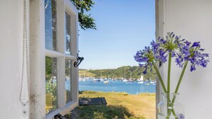A window with a clear view of a harbor, boats, and a vase with flowers. - 4 bedroom accommodation in Portscatho (Portscatho)