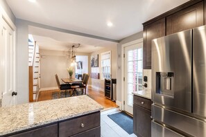 A modern kitchen with a stainless steel refrigerator, granite countertop, and wooden flooring. - Green on Fleet 1 Block to City Dock & USNA w Parking (Annapolis)