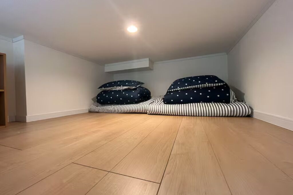 A room with two bean bags on a wooden floor, white walls, and a ceiling light.