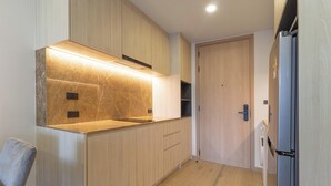 Cozinha moderna com armários de madeira, forno embutido e geladeira de aço inoxidável.