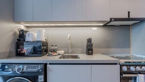Una cocina compacta con lavadora, cafetera, fregadero y estufa.