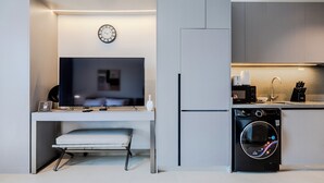 Cocina compacta con lavadora integrada, televisor de pantalla plana y diseño minimalista.