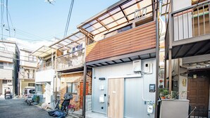 A residential building with a wooden balcony, a garage door, and a parked bicycle. - TEN6-TenSix- (Osaka)