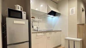 A modern kitchen with a built-in microwave, a stainless steel refrigerator, and a compact sink area. - TEN6-TenSix- (Osaka)